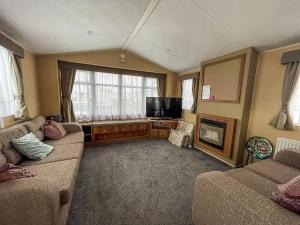 sala de estar con sofá y TV de pantalla plana en Lovely Caravan With Decking And Free Wifi At Valley Farm, Essex Ref 46610v, en Great Clacton