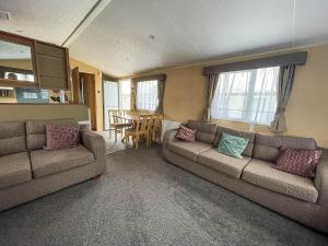 Sala de estar con 2 sofás y mesa en Lovely Caravan With Decking And Free Wifi At Valley Farm, Essex Ref 46610v, en Great Clacton