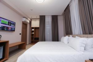 a bedroom with a white bed and a flat screen tv at Residence Inn Hotel in Tirana