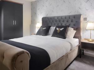 a bedroom with a large bed with a blue headboard at Acre Hill Lodge in Harrop Fold