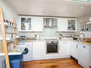 una cucina con armadietti bianchi e lavastoviglie di The Little Beach House a Brighton & Hove
