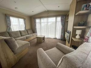 uma sala de estar com um sofá, cadeiras e janelas em Modern 6 Berth Caravan With Free Wifi Nearby Pakefield Beach Ref 68028cr em Lowestoft