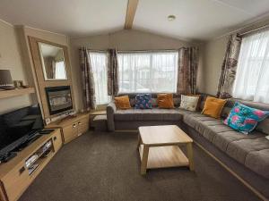 sala de estar con sofá y mesa en Great 4 Berth Caravan With Wheelchair Access In Suffolk, Ref 68129bs en Lowestoft