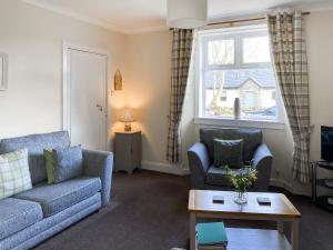 a living room with two couches and a window at Kirnan Cottage in Kilmichael Glassary