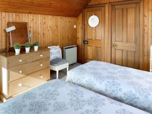 a bedroom with two beds and a dresser and a chair at Kirnan Cottage in Kilmichael Glassary