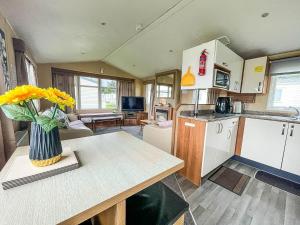 a kitchen with a table and a vase of yellow flowers at Wonderful 8 Berth Caravan At Valley Farm Nearby Clacton-on-sea Ref 46396v in Great Clacton