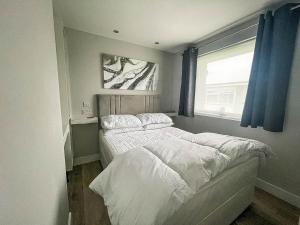 a bedroom with a large bed with a window at Beautiful Chalet In The Seaside Village Of Scratby, Norfolk Ref 51054s in Great Yarmouth