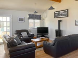 a living room with two leather couches and a tv at The Beeches in Warkworth