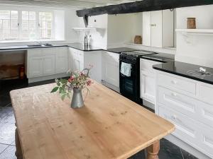 a kitchen with a wooden table with a vase of flowers on it at Ashford Old Farm in Ilton