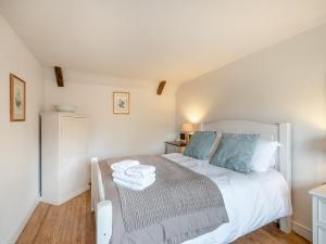 a bedroom with a white bed with blue pillows at Swallow Cottages, No 2 - Uk46810 in Thurgarton
