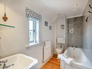 a white bathroom with a tub and a toilet at Swallow Cottages, No 2 - Uk46810 in Thurgarton +5 photos