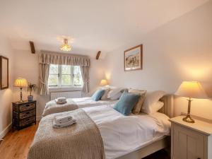 a bedroom with a large bed with white sheets and blue pillows at Swallow Cottages, No 1 - Uk46811 in Thurgarton