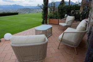 a patio with wicker chairs and tables and a lawn at Tenuta Cantona in Casole dʼElsa