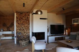 a living room with a tv and a pile of fire wood at Centrum Terapii Leśnej in Zawoja