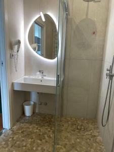 bagno con doccia, lavandino e specchio di Hotel Golden a Rimini