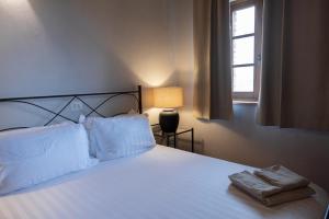 a bedroom with a bed with white sheets and a window at Tenuta Cantona in Casole dʼElsa