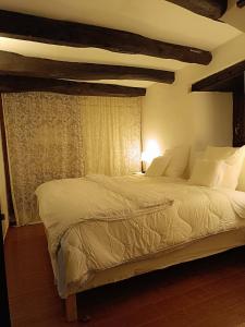 um quarto com uma cama grande e lençóis brancos em small House of La Reguera 