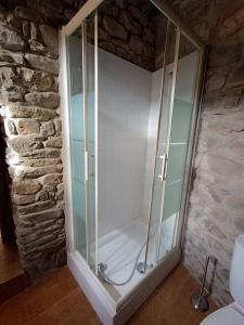 uma cabina de duche em vidro numa casa de banho com uma parede de pedra em small House of La Reguera 