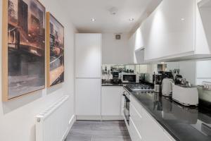 a kitchen with white cabinets and black counter tops at Gloucester Place/Marylebone Apartments in London
