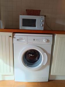 um micro-ondas em cima de uma máquina de lavar roupa numa cozinha em small House of La Reguera 