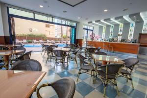 a restaurant with tables and chairs and a pool at Hotel Cibeles Playa in Gandía