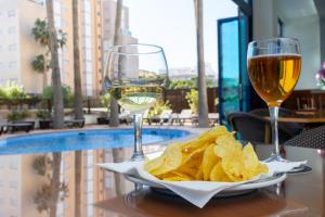 una mesa con dos copas de vino y patatas fritas en Hotel Cibeles Playa, en Gandía