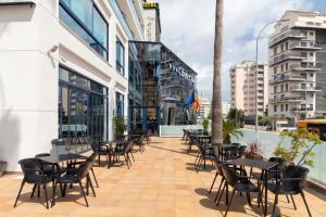 eine Terrasse mit Tischen und Stühlen auf einem Gebäude in der Unterkunft Hotel Cibeles Playa in Gandía