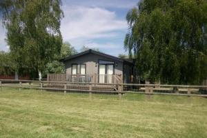 ein winziges Haus auf einem Feld neben einem Zaun in der Unterkunft Puddledock - luxury lodge - Kent countryside in Brookland