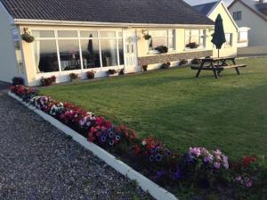 a house with a picnic table and flowers in the yard at Seaside Accomodation in Quilty