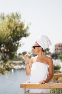 Una donna seduta su una panchina che beve un bicchiere di vino di Medusa Luxury Suites a Néos Marmarás