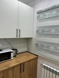 La cuisine est équipée de placards blancs et d'un four micro-ondes. dans l'établissement 3х комнатная квартира, à Chimkent