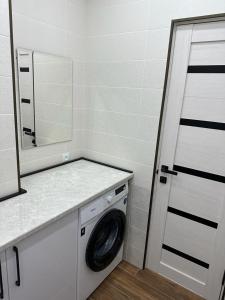 - un lave-linge dans la salle de bains pourvue d'un miroir dans l'établissement 3х комнатная квартира, à Chimkent