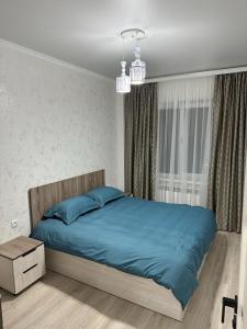 a bedroom with a blue bed and a window at 3х комнатная квартира in Shymkent