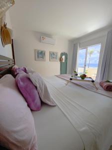 een slaapkamer met een groot wit bed en een raam bij Ondas de Marina pé na areia - BAHIA in Lauro de Freitas