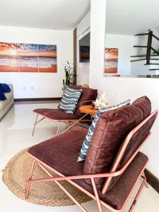 een woonkamer met 2 stoelen en een tafel bij Ondas de Marina pé na areia - BAHIA in Lauro de Freitas