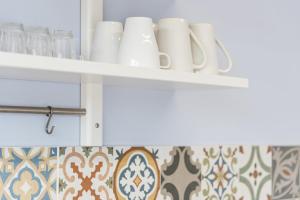 ein Regal mit Tassen und Gläsern in der Küche in der Unterkunft GuestReady - Wellspring Bloom in Porto