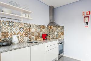 eine Küche mit weißen Schränken und Wandfliesen in der Unterkunft GuestReady - Wellspring Bloom in Porto