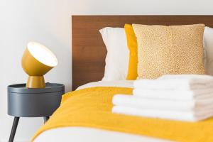 Una cama con una manta amarilla y una lámpara. en GuestReady - Aptos do Hemisfério, en Oporto