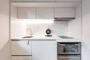 a white kitchen with white cabinets and a sink at GuestReady - Three Mirrors in Porto