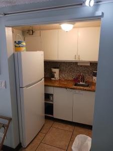 a kitchen with white cabinets and a white refrigerator at Diamond Head Beach Hotel in Honolulu
