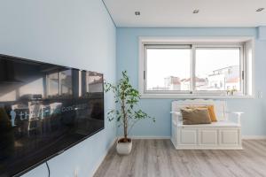 ein Wohnzimmer mit einem großen TV und einem weißen Sofa in der Unterkunft GuestReady - Assuntos de recreio in Porto