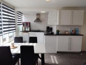 a kitchen with white cabinets and a table with chairs at ZEESTER in Meliskerke