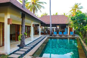 a villa with a swimming pool in front of a house at Dolce Magia in Gili Trawangan
