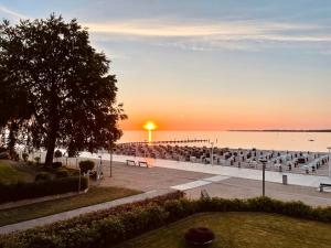 a sunset over the water with benches and a pier at Strand Suite in Lübeck