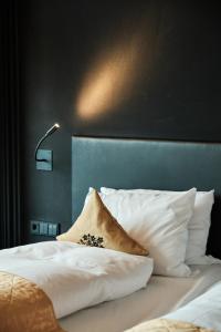 Una cama con almohadas blancas y una lámpara. en Kameha Grand Bonn en Bonn