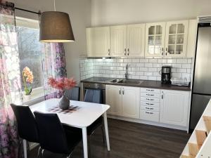 una cucina con armadi bianchi e tavolo con sedie di Newly built guest house located in Vimmerby a Vimmerby