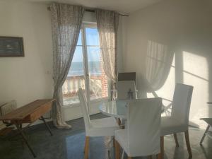 a dining room with a table and chairs and a window at La Villa de Puys - Dieppe in Dieppe