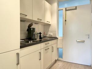 uma cozinha branca com armários brancos e uma porta em Strand Suite em Lübeck