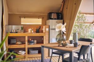 a kitchen with a table and a refrigerator at Le Vallon aux merlettes in Matignon