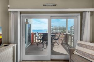 een woonkamer met een glazen schuifdeur met uitzicht op de oceaan bij Baywatch C8 in Pensacola Beach